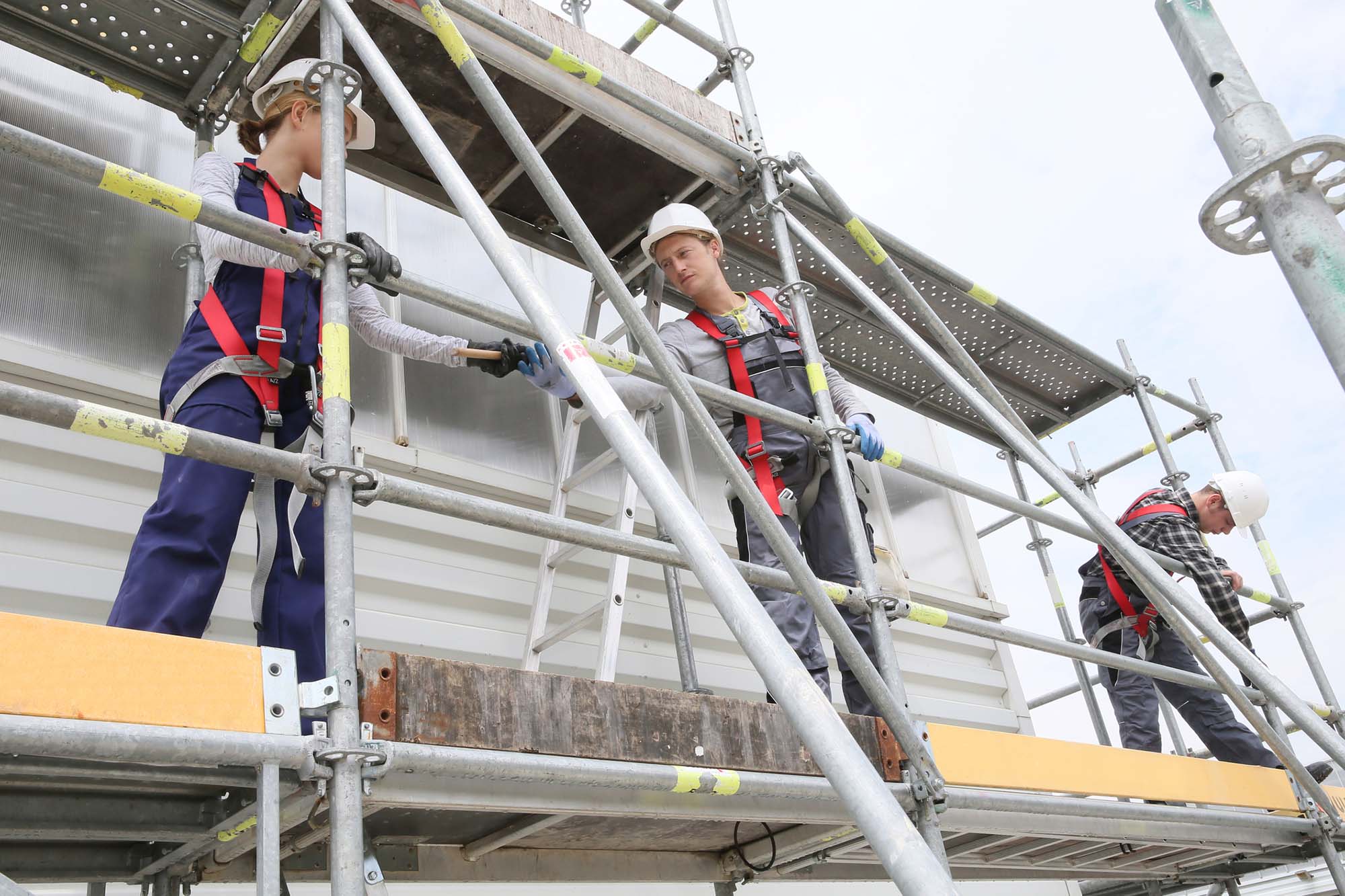 Construction workers installing scaffolding on site