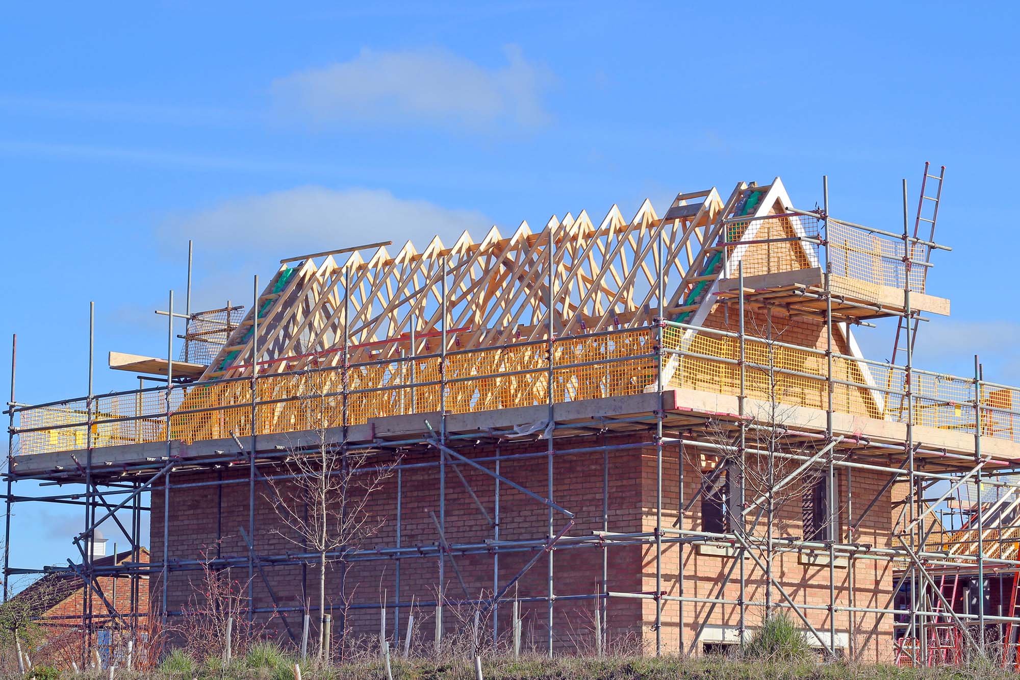 New build house with roof rafters and scaffolding. A new build house under construction showing wooden roof beams and scaffolding.